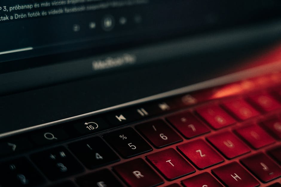 A vibrant close-up of a backlit laptop keyboard with a glowing red hue, showcasing modern technology.