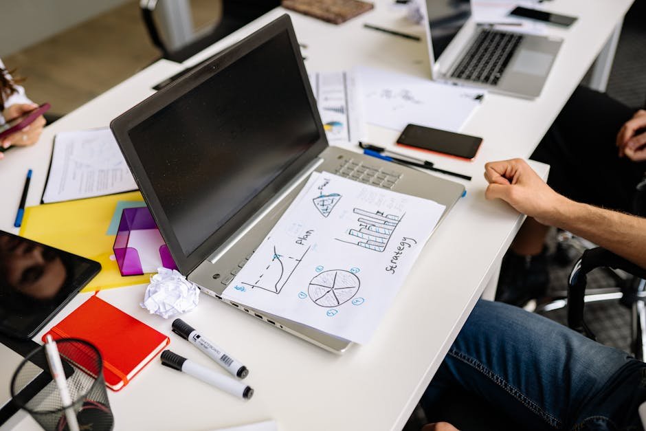 Focused group working on business strategy with laptop and charts at modern workplace.