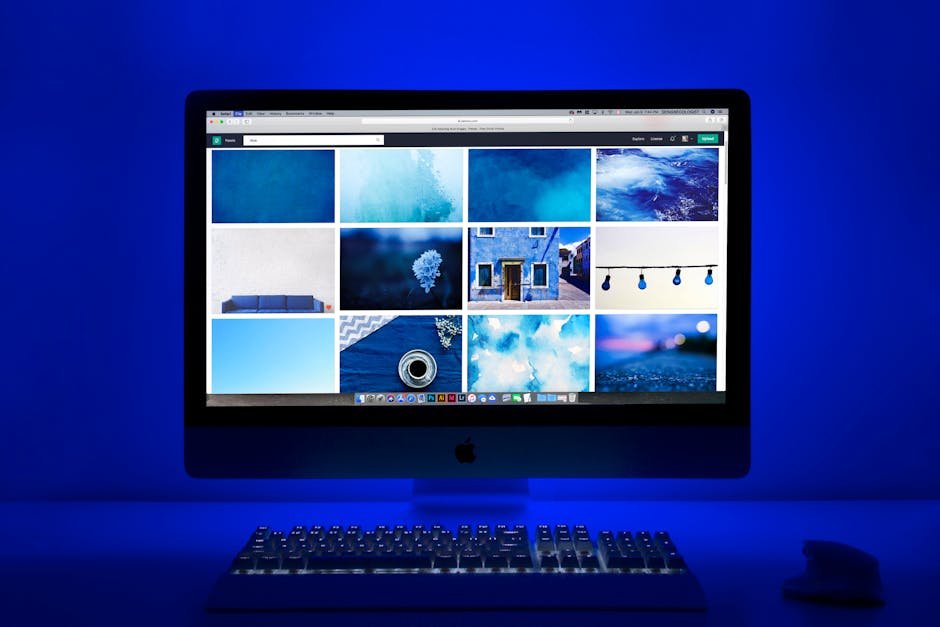 Modern workspace with a glowing blue theme and a computer monitor showcasing a gallery of images.