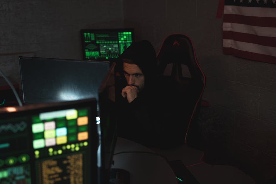 A cybersecurity expert monitors multiple screens, focused on data protection in a dark room.