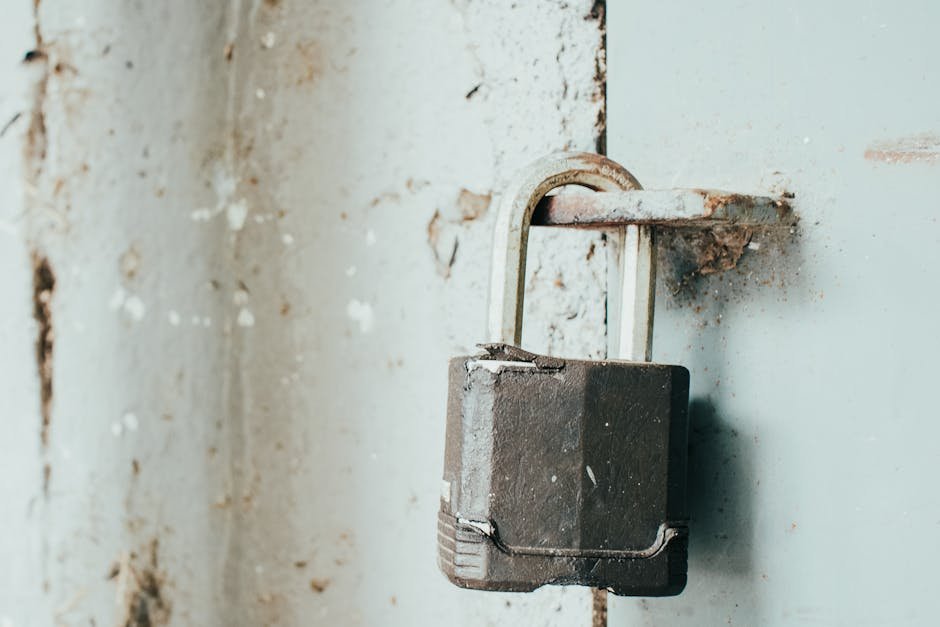 Detailed close-up of a rusty padlock securing a weathered door, highlighting age and texture.