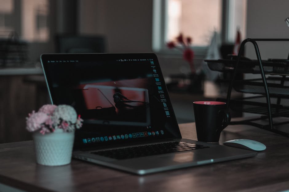 Cozy indoor workspace featuring a laptop, coffee mug, and flowers for a productive environment.