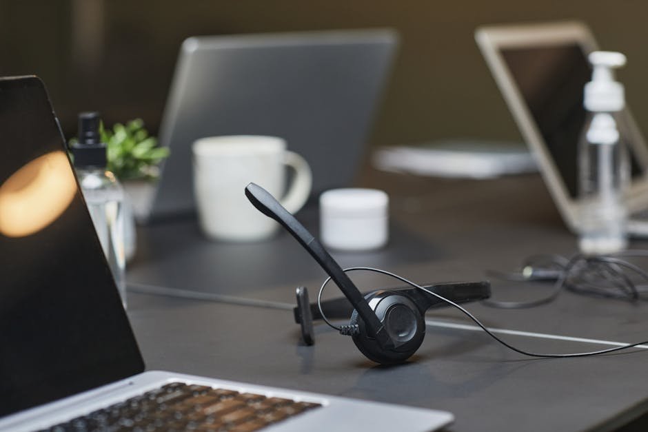 A contemporary office desk setup featuring headphones, laptops, and office essentials for a productive work environment.