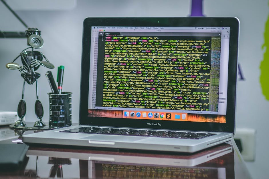 A sleek MacBook Pro displaying code on a desk with office tools and creative decorations.