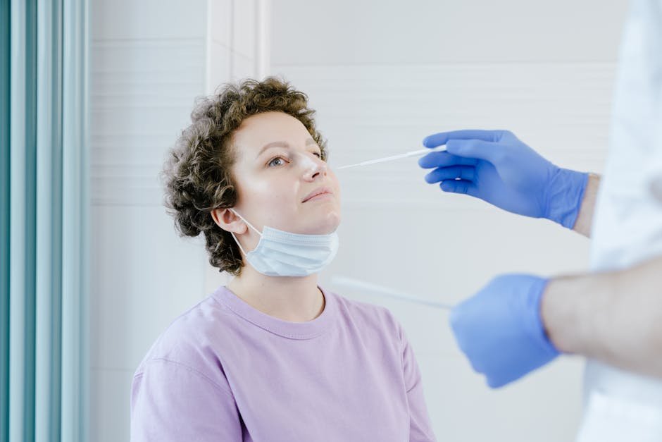 Healthcare worker administering a COVID-19 swab test to a patient indoors.