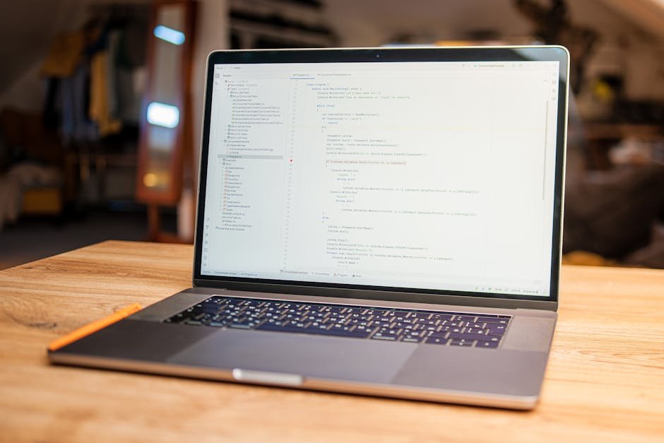 Open laptop with visible code on screen on a wooden desk in a modern, cozy workspace.